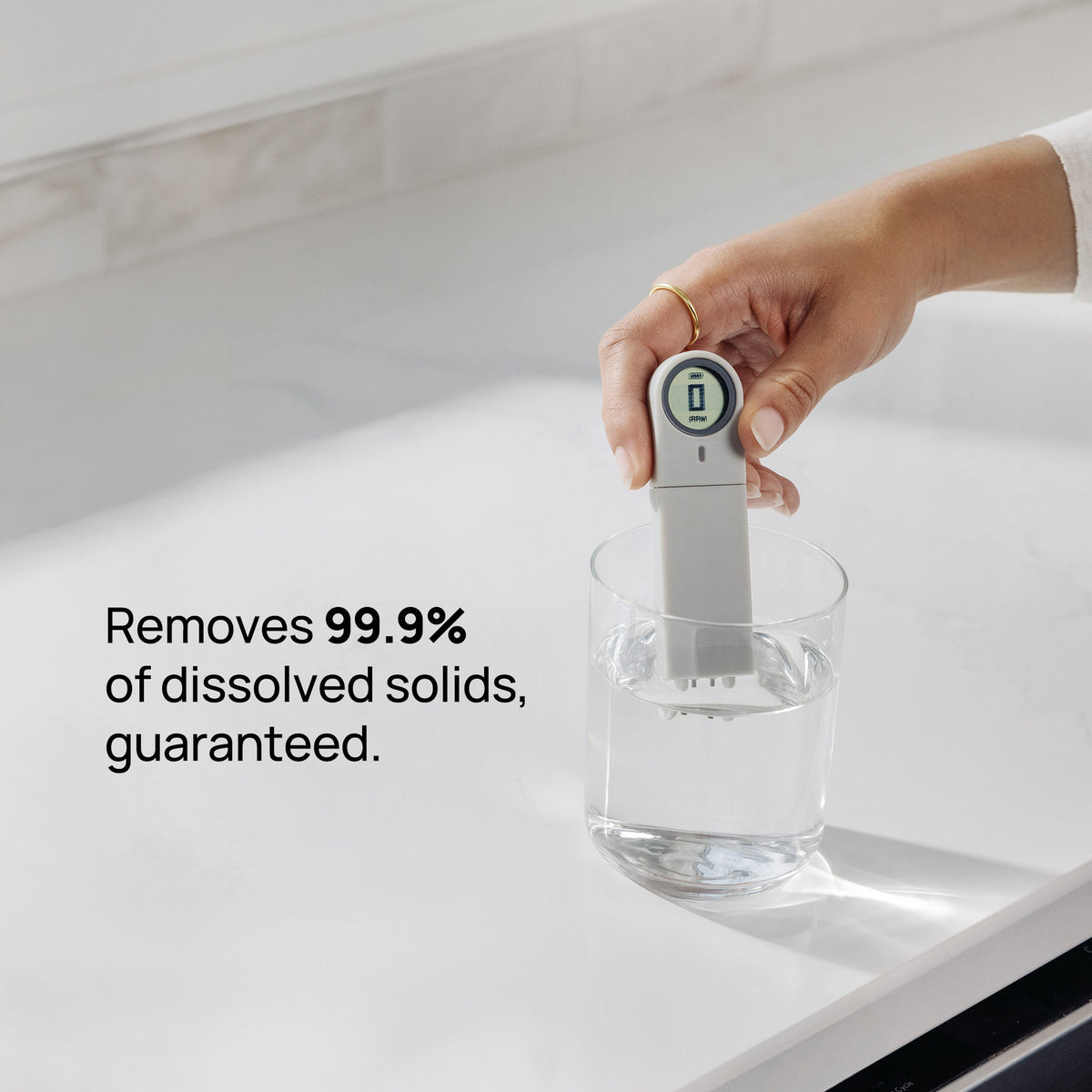 Person testing water in glass with TDS meter